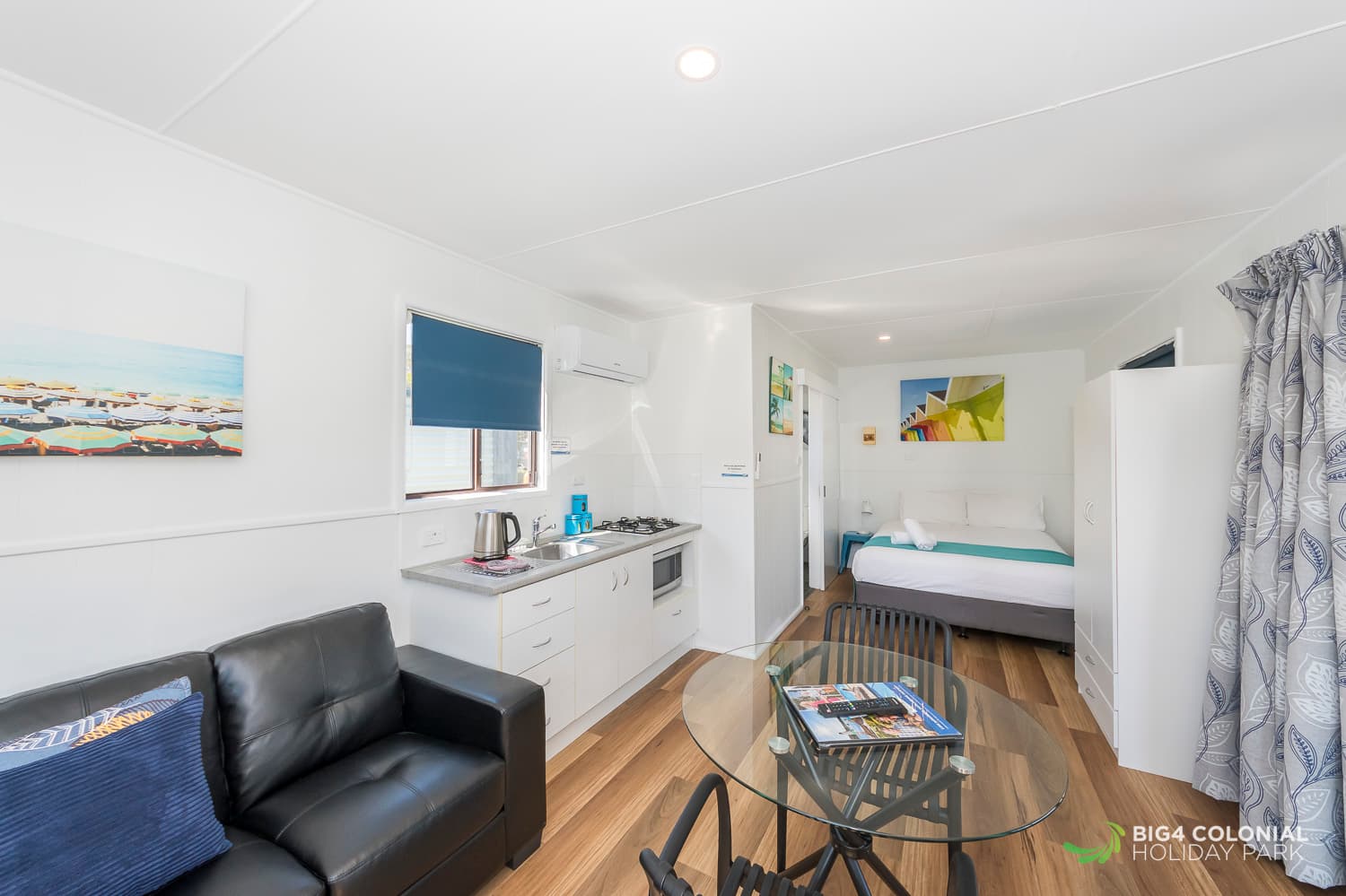 Three seater couch, kitchenette, dining table and queen bed of studio cabins. 