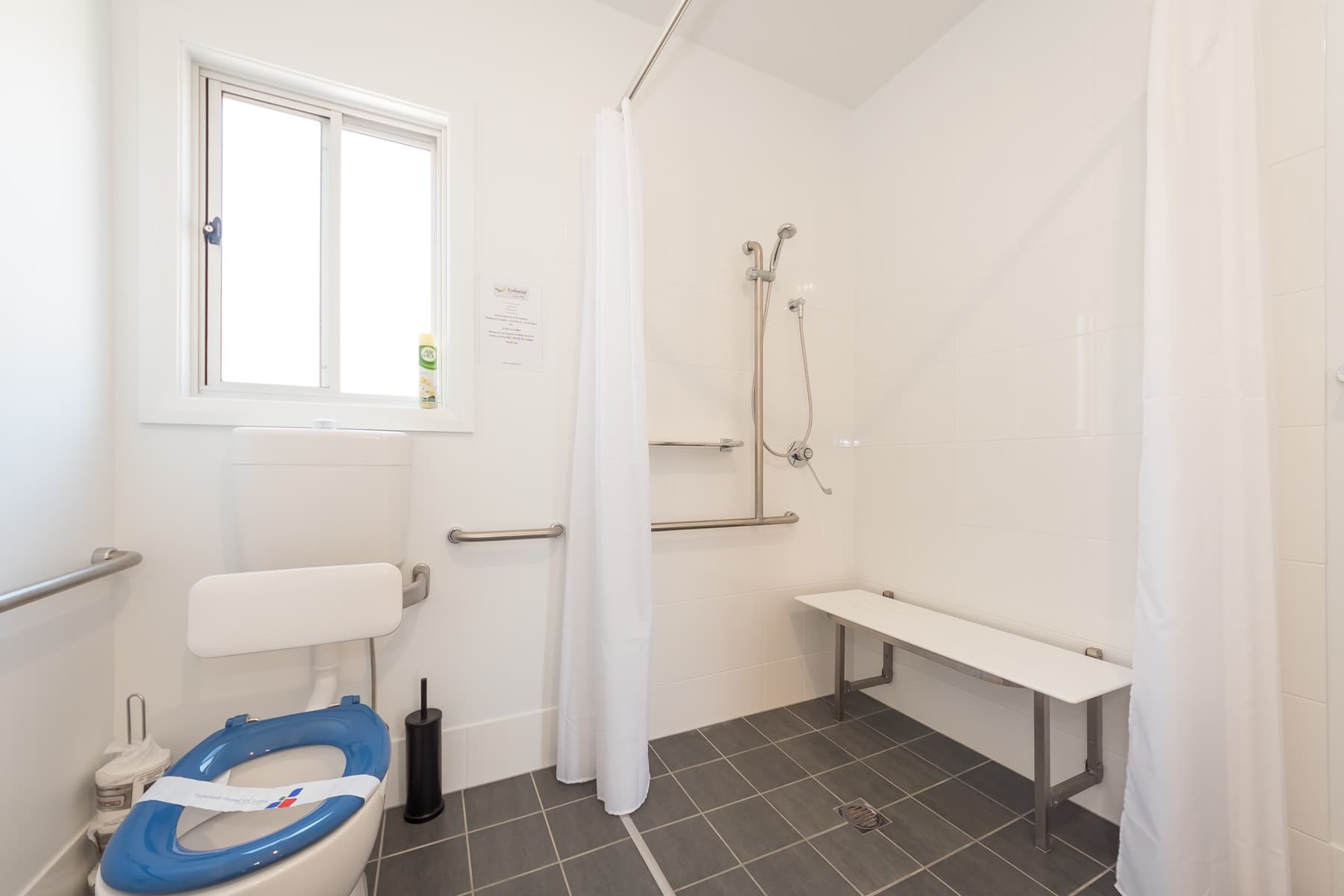 Bathroom with fold down shower chair in Acessible Executive Two Bedroom Villa. 