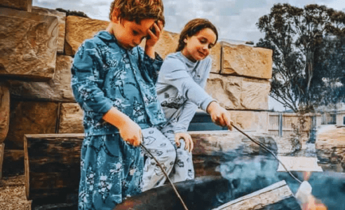Kids are toasting marshmallows on the open fir in front of their glamping tent